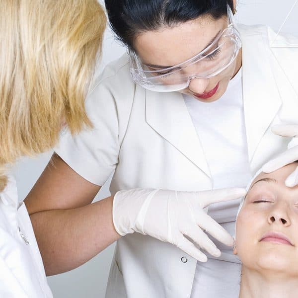 An instructor guiding a student through a treatment on a client in a clinic