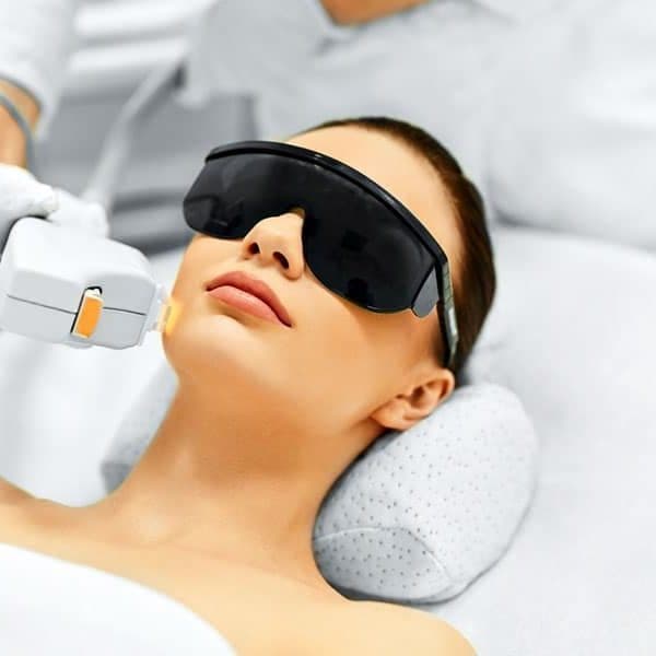 Client in protective eyewear during an advanced laser facial resurfacing treatment, taught at Master Practitioner level