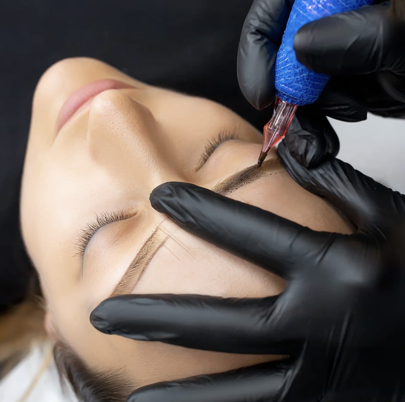 A technician performing ombre powder brow shading with a PMU device